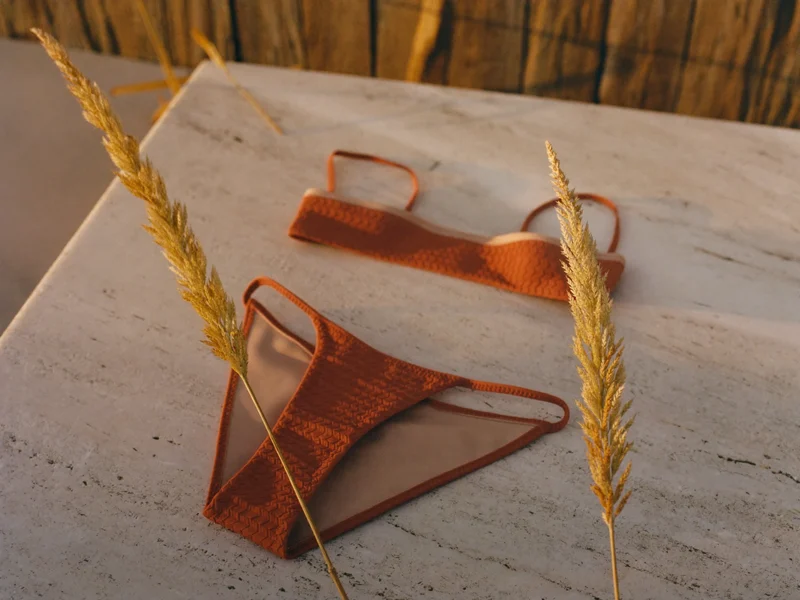 Zweiteiliges Bikini-Set in Terrakotta und Sand auf hellem Travertin