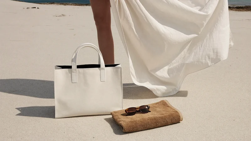 Strandtag-Stillleben mit Tasche, Handtuch, Sonnenbrille und Kaftan im Gegenlicht